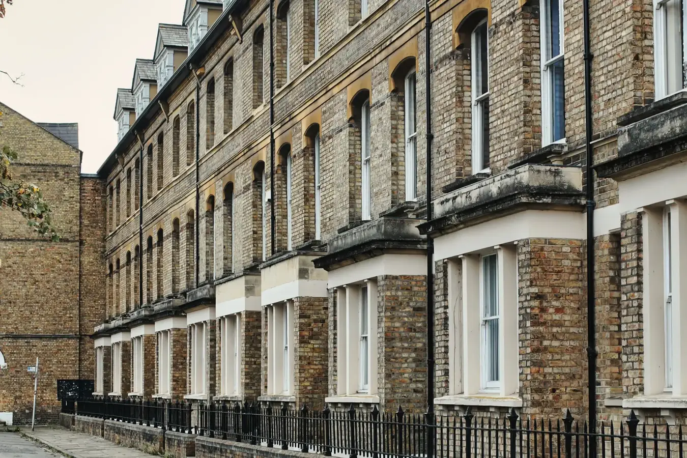 A row of Victorian brick terraced houses behind iron railings