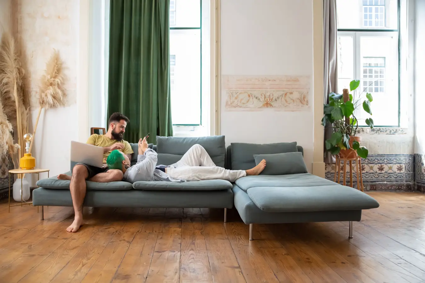 Two people relaxing on a sofa in a high-ceilinged flat